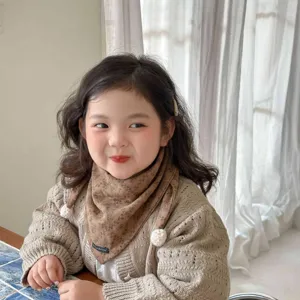 Charming toddler girl wearing brown floral print triangle scarf and warm knit cardigan detail.
