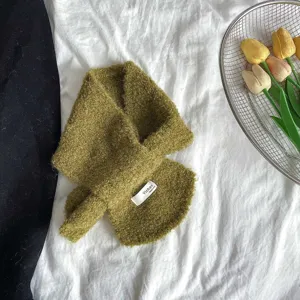 Close-up view of the green textured loop yarn kids cross scarf showing fabric brand label.