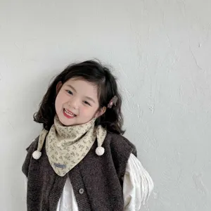Detail view of a thick windproof toddler girls triangular scarf with cute pom pom accents.
