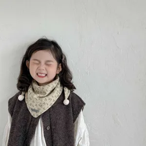 Detailed shot of a cute toddler girl wearing a cozy floral print baby triangle scarf winter.