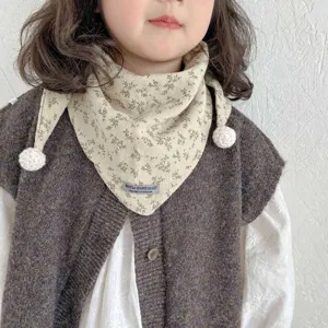 Close-up detail of toddler floral triangle scarf with cute pom-pom ends for cozy autumn wear.