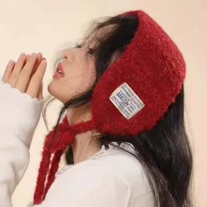 Detailed view of a cozy red knitted ear warmer hat with cute straps for winter warmth.