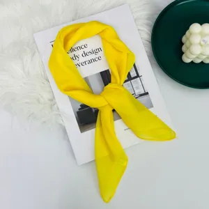 Dettaglio di un foulard quadrato in seta giallo vivo, tessuto leggero e morbido per look eleganti.