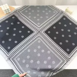 Detail view of a retro grey square silk scarf with geometric borders and elegant printed floral motifs.