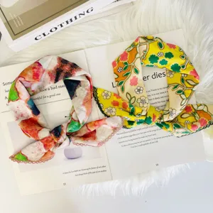 Detailed close-up of colorful floral print scarves on a stylish book prop and fluffy background.