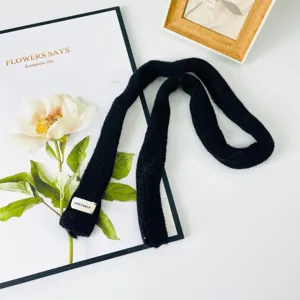 Vista dettagliata della sciarpa in maglia nera, tessuto morbido, elegante accessorio.