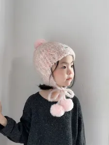 Vue détaillée d'un joli bonnet d'hiver rose en tricot pour tout-petit avec oreillettes et pompons.