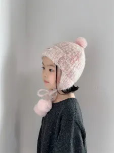 Gros plan sur les détails du bonnet chaud en tricot rose pour enfants avec pompon mignon.