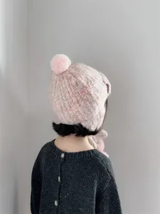 Vue détaillée du bonnet d'hiver en tricot pour enfants avec pompon et rabats d'oreilles.