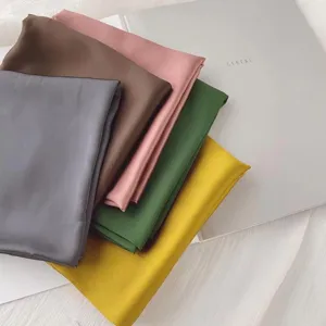 Details of solid color silk square scarf, soft glossy texture, versatile elegant neck accessory.