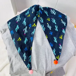 Children's triangle scarf detail shot, dark blue cactus print fabric with cute pom poms.