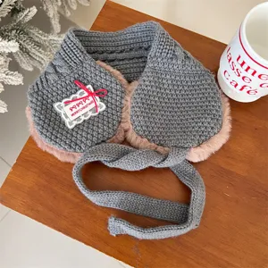 Detailed view of children's grey knitted earmuffs with plush lining and bow tag for winter.