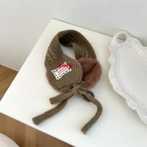 Detail of brown knitted winter earmuffs for kids, featuring soft plush lining and cute bow tie.