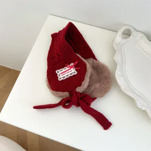 Kids red knitted earmuffs detail view, winter warm furry ear warmers with cute bow tie.