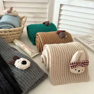 Detailed view of cute children's winter knit scarf with plush animal decor in various colors.