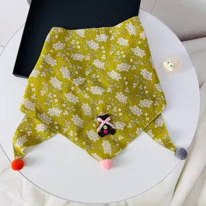 Detailed view of the cute floral baby triangular scarf with pom-pom and bear decor.