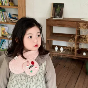 Close-up detail of the cute pink knitted kids winter scarf with charming Christmas decorations.