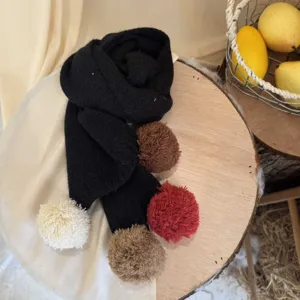 Vue detaillee de l'echarpe tricotee pour enfants avec de jolis pompons colores et doux.
