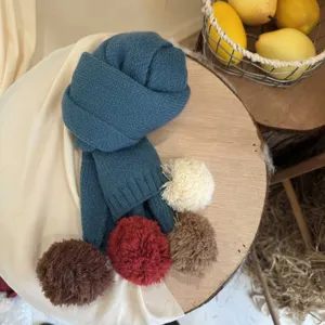 Écharpe en tricot pour enfants avec pompons colorés pour un automne et hiver douillet.