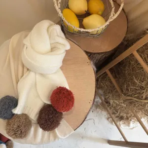 Vue de détail d'une écharpe tricotée élégante pour enfants avec pompons colorés, tour de cou chaud.
