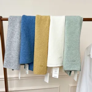 Cozy solid color knitted scarf detail showcasing soft texture and hanging tags style.