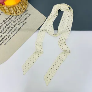 Vista dettagliata di un foulard lungo a pois color crema, accessorio elegante.