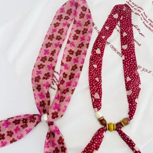 Detail shot of retro floral and heart print ribbon silk scarf necklace with beads for women.