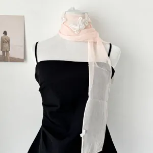 Primo piano dettaglio della elegante sciarpa stretta in chiffon rosa con farfalle in pizzo.