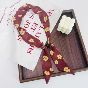 Close-up detail of the retro floral skinny scarf with black bead accent on wooden tray.