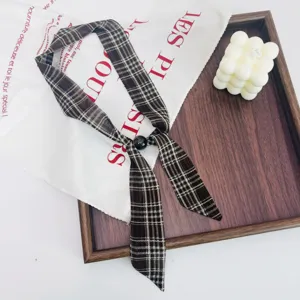 Detailed shot of a vintage plaid scarf necklace with black bead, artistic neck ribbon.