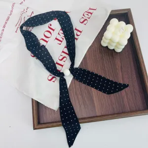 Detailed close-up of the black polka dot silk scarf necklace with a elegant pearl bead accent.