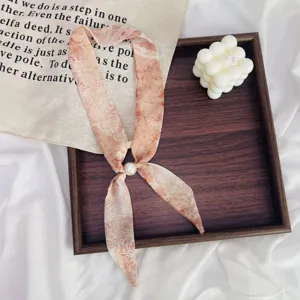 Detailed view of a retro floral skinny scarf with a pearl buckle, perfect for stylish neckwear.