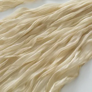 Dettaglio ravvicinato di tessuto per sciarpa velato stropicciato leggero, oro champagne.