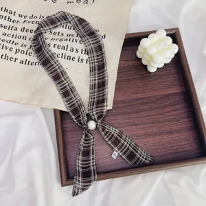 Detailed view of the vintage brown plaid skinny scarf with a pearl buckle ornament.