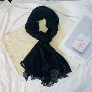 Detailed view of a black crinkled lightweight scarf, breathable fabric and stylish drape.