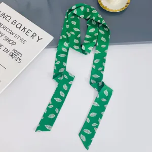 Close-up of green long silk scarf ribbon with white leaf print, versatile neck and hair accessory.