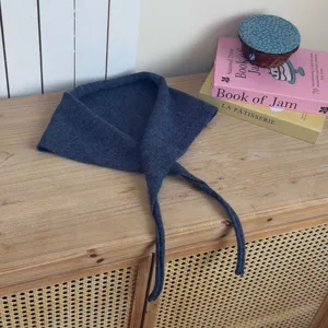 Detailed view of the dark blue knitted triangular scarf with strings for stylish autumn wear.