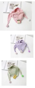 Detail shot of cute baby cotton plaid scarf with cartoon plush charm and pom-pom decor.