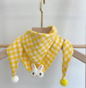 Close up view of baby yellow plaid scarf featuring cute plush rabbit head and soft pom-poms.