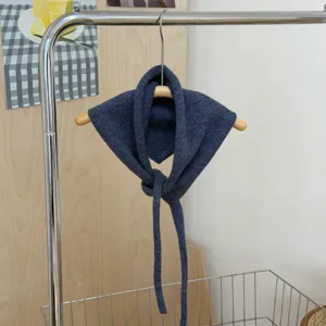 Dark blue knitted triangular scarf detail, soft neckerchief with long ties, cozy winter style.