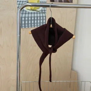Detail shot of a solid brown knitted triangular scarf with long ties, versatile daily accessory.