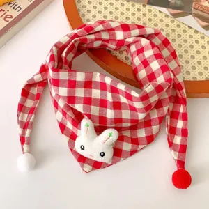 Close-up of cute baby red white plaid scarf with bunny plush detail and soft pom-poms.
