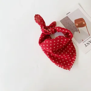 Detailed view of the red plaid baby scarf knot, showing soft fabric and delicate gold pattern details.