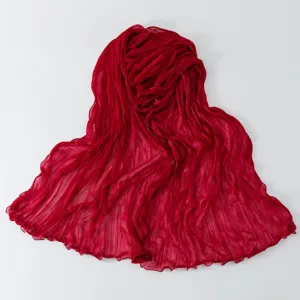 Vista dettagliata della sciarpa in garza rossa leggera con delicato bordo ondulato.