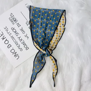 Detail shot of a double-sided plaid scarf with blue and yellow checkered pattern and black trim.