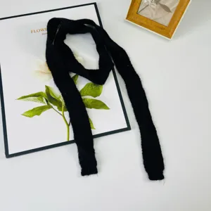 Dettaglio sciarpa fine in maglia nera, foulard lungo minimalista, accesorio versatile.