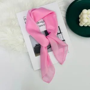 Dettaglio di un foulard quadrato in seta rosa chiaro, accessorio elegante e leggero.