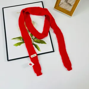 Dettaglio sciarpa a maglia rossa stretta che mostra tessuto morbido e decorazione etichetta.