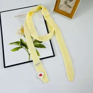 Primo piano di una morbida sciarpa tubolare in maglia gialla con etichetta, ideale in autunno.