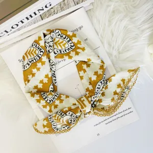 Detail of a stylish mustard yellow and white square silk scarf with delicate lace trim.